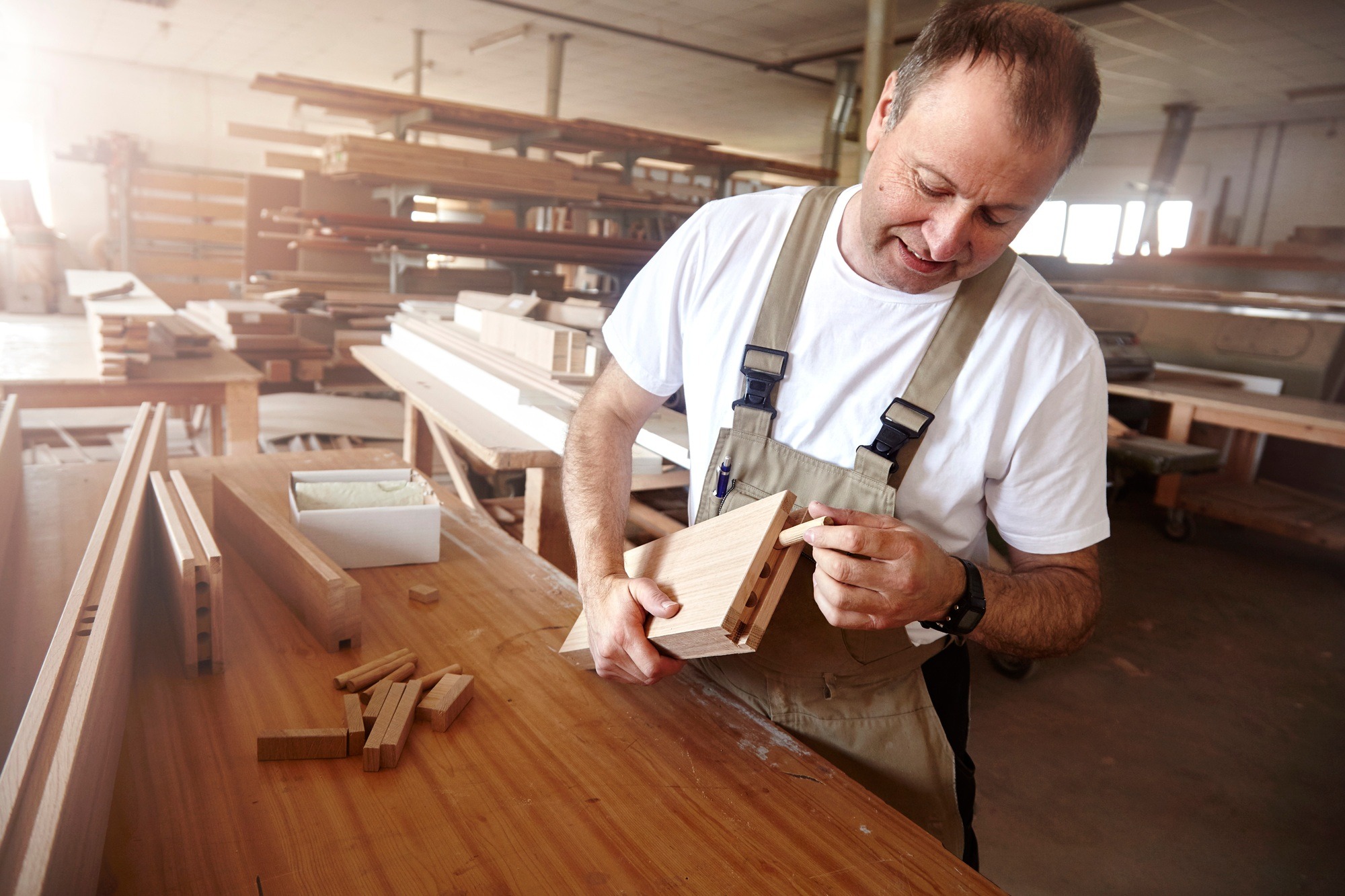 Male carpenter inserting wooden dowel at workbench